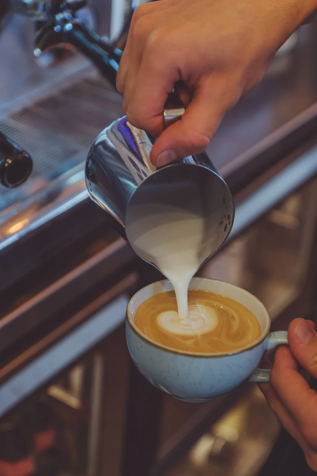 Milch eingießen und Latte Art in der Tasse